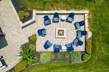 A fire pit surrounded by blue chairs in a garden.